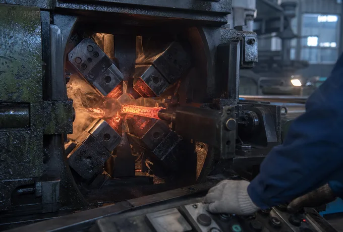 Radial precision forging machine closing on a hot tool steel bar