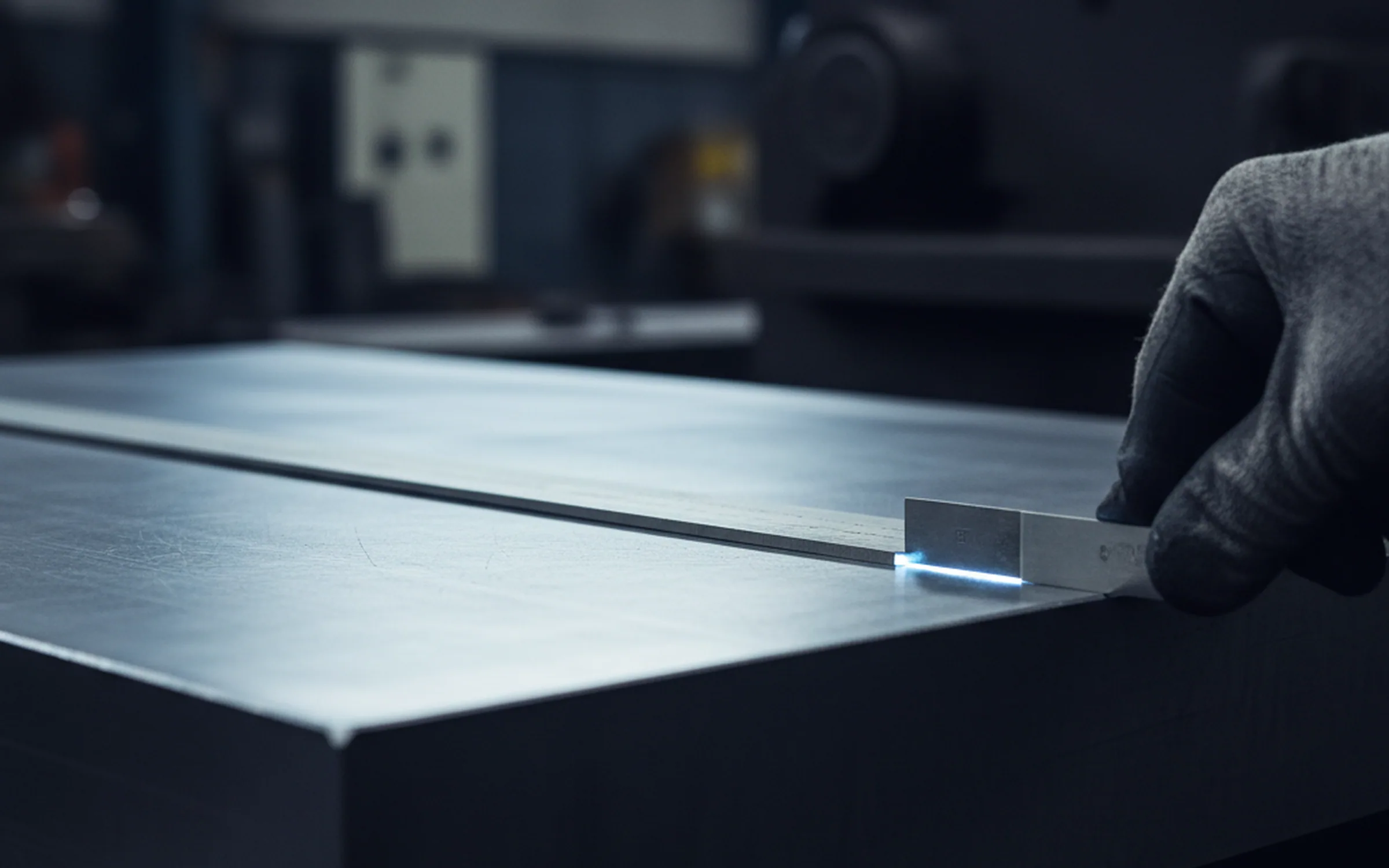 Straightedge laid along a ground tool steel plate with a feeler gauge in the gap after tool steel surface grinding